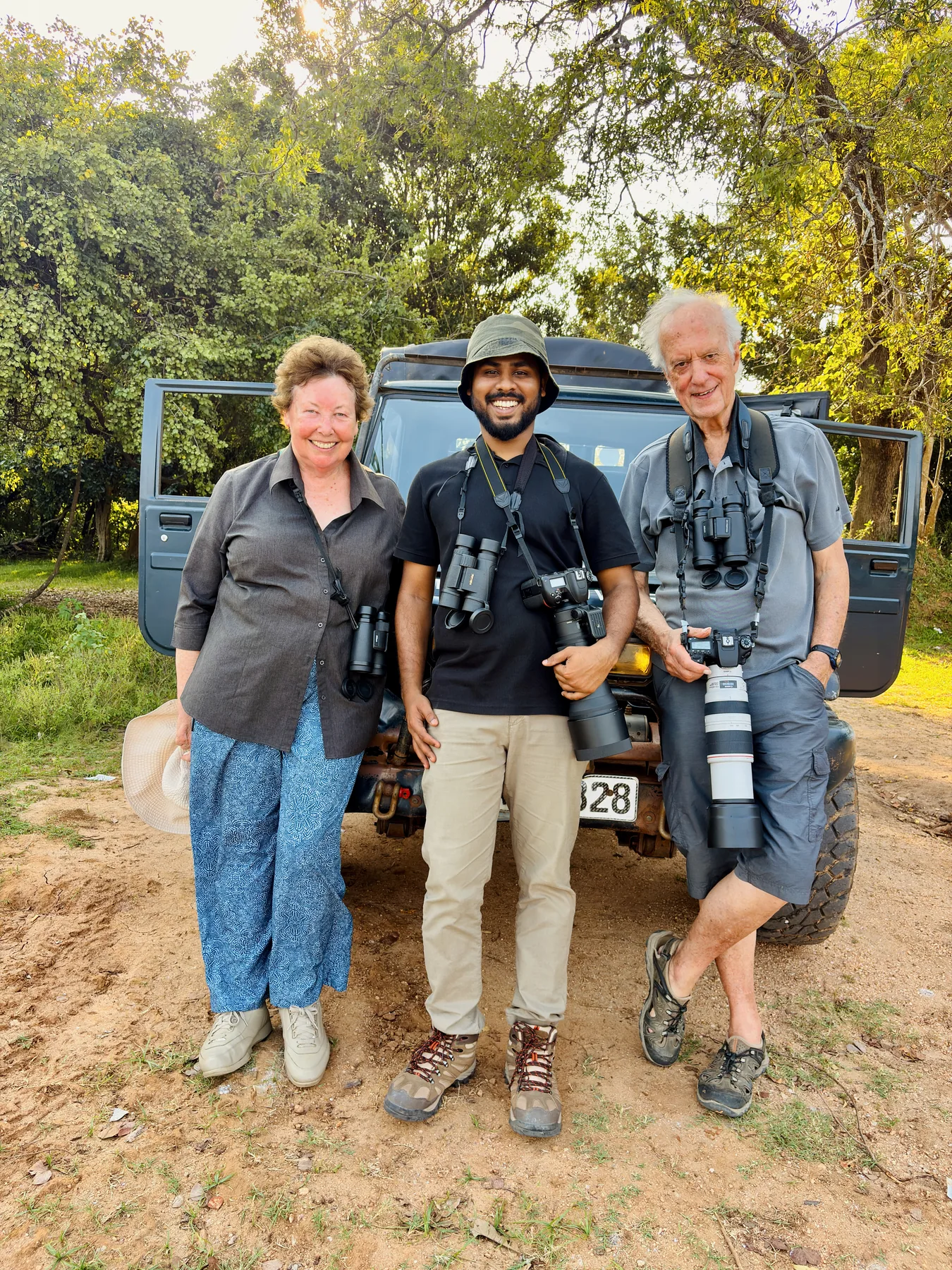 Sahan standing with fellow wildlife photographers beside a field vehicle