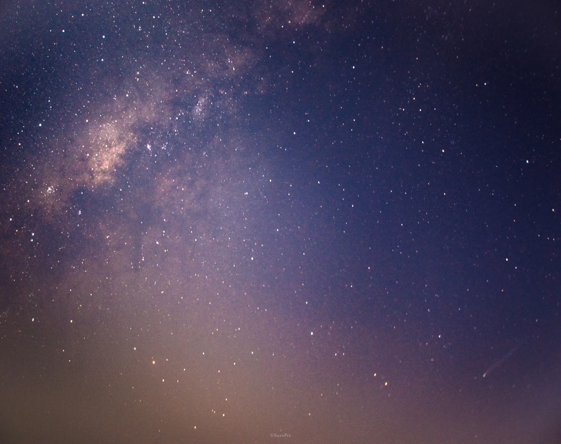 Comet within a wide star field in a purple night sky