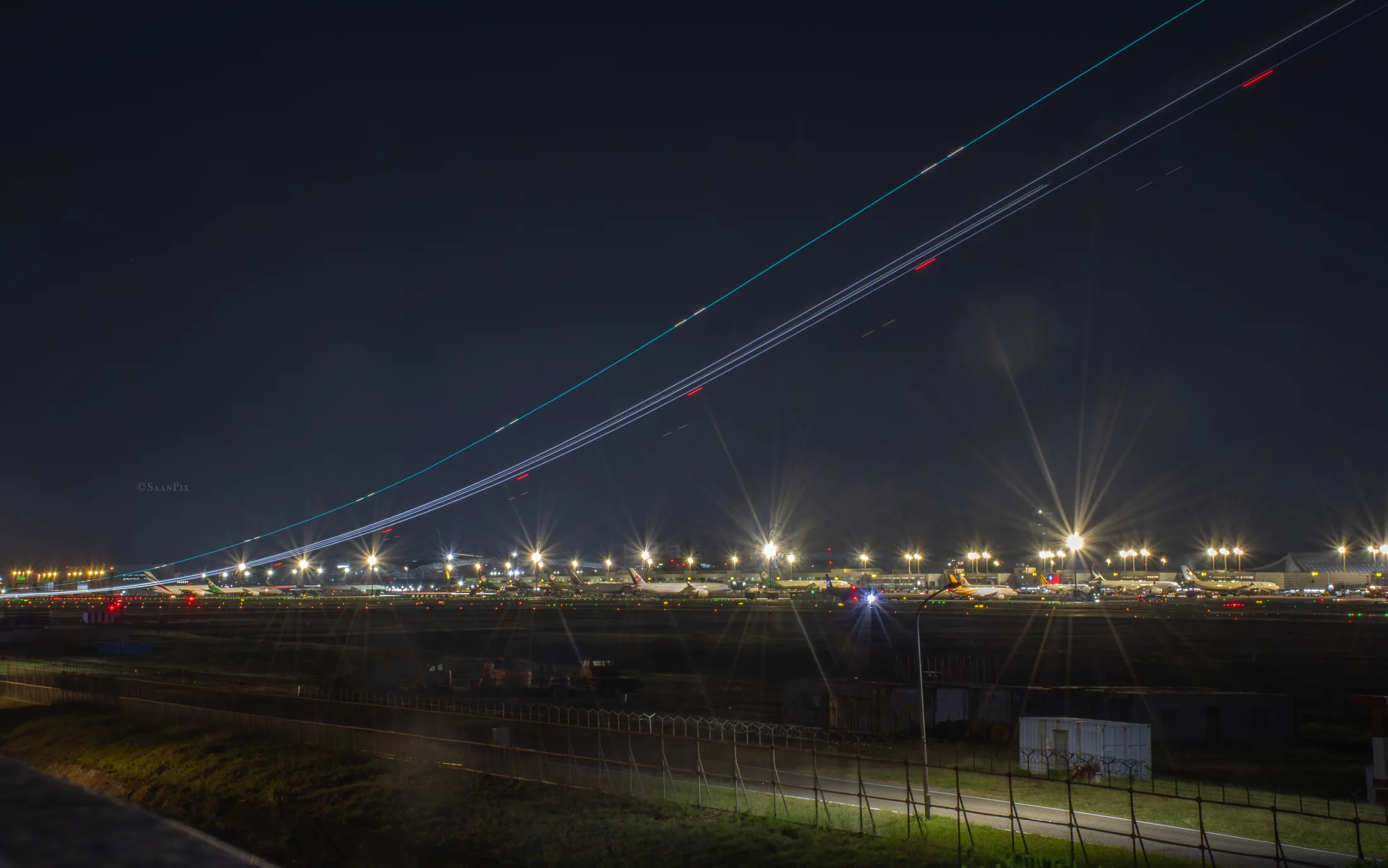 Long-exposure aircraft light trails above an airport at night