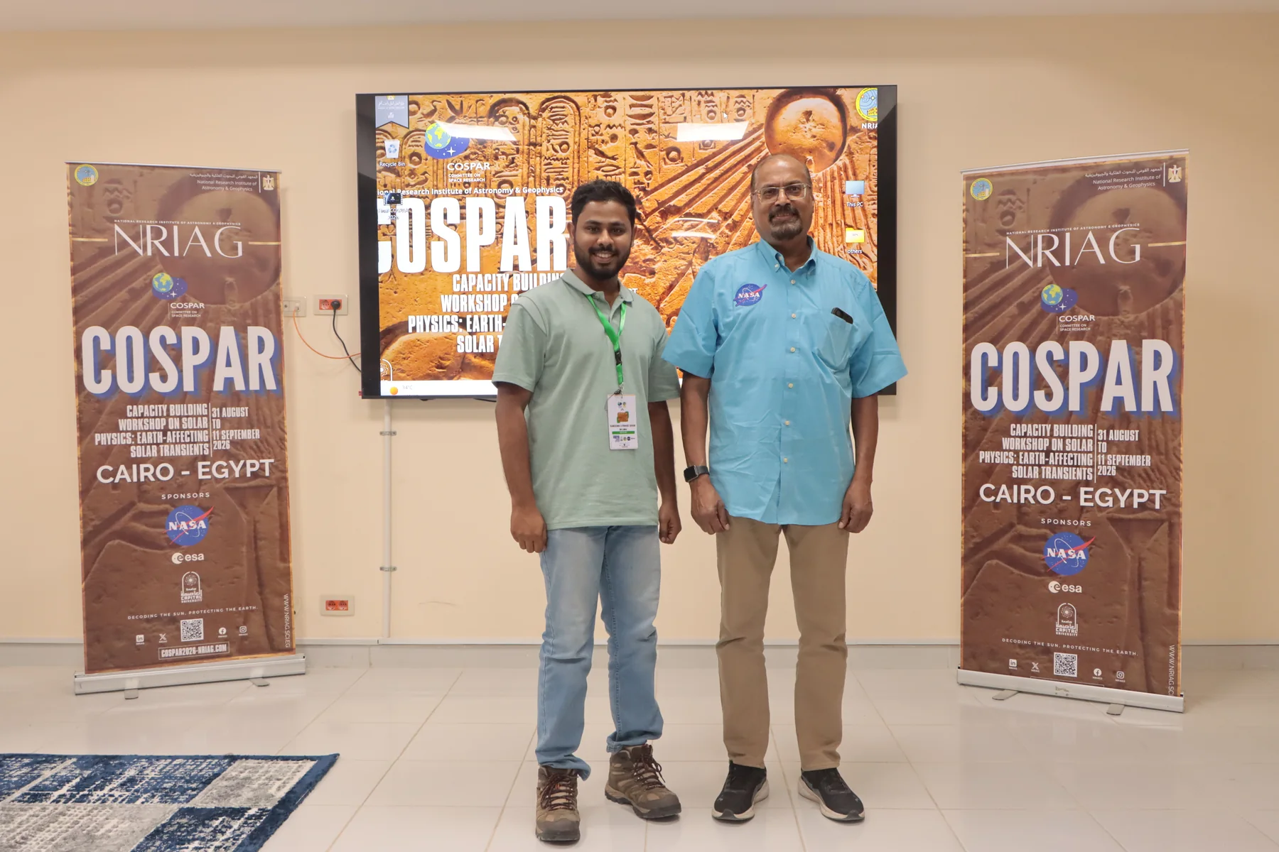 Sahan with a colleague beside the COSPAR 2026 workshop banners
